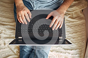 Top view of male hands using modern laptop, close up of young man working at home and using notebook computer, man`s