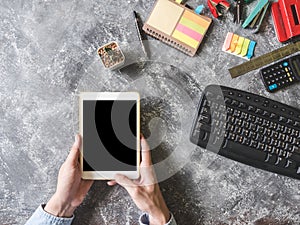 Top view of Male hands using Tablet with Office supplies on grunge gray background.