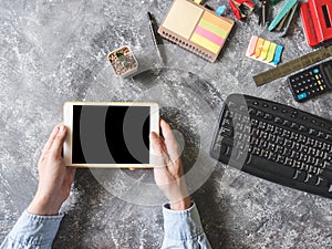 Top view of Male hands using Tablet with Office supplies on grunge gray background.