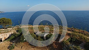 Top view of the Mamula fortress, rocky coast, seagulls flying over it, and the sea horizon