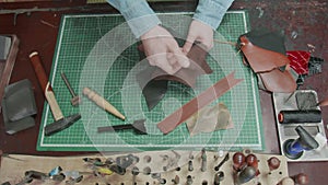 Top view on man chooses leather for new belt or wallet. Working process in the leather workshop.