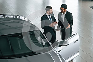 Top view. Man is consulting the customer in the car showroom