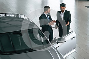 Top view. Man is consulting the customer in the car showroom