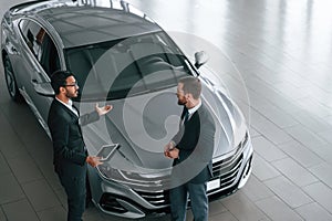 Top view. Man is consulting the customer in the car showroom