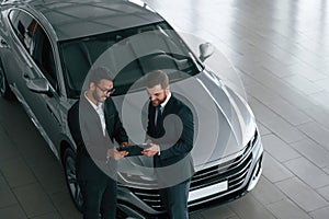 Top view. Man is consulting the customer in the car showroom