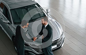 Top view. Man is consulting the customer in the car showroom