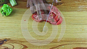 Top view on man hands cut by knife slices of tomato on pieces on wooden table
