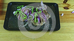 Top view on man hands decorating with purpule onion slices half of raw chicken