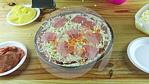 Top view on man by hands grate carrot on raw pizza with different ingredients