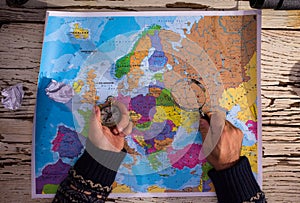 Top view of man hands holding a compass ona europe map