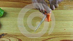 Top view on man hands by knife cut into halves part of cleaned fresh carrot