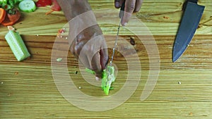 Top view on man hands by knife cut on pieces large green bell pepper on table