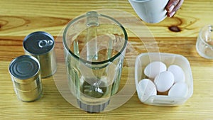 Top view on man hands pour milk from white cup into glass chalice on table