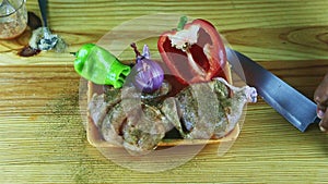 Top view on man hands put knife next to marinaded in herbs chicken with vegetables