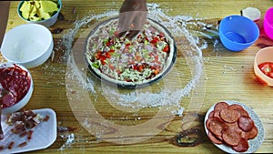 Top view on man hands put onion pieces on semifinished pizza with sauce and cheese