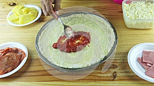 Top view on man hands put onion pieces on semifinished pizza with sauce and cheese