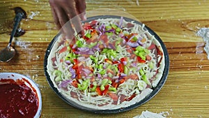 Top view on man hands put onion pieces on semifinished pizza with sauce and cheese