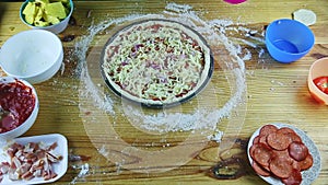 Top view on man hands put onion pieces on semifinished pizza with sauce and cheese