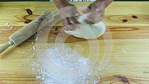 Top view on man by hands quickly knead white dough on wooden table