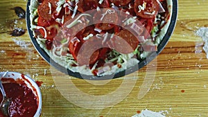 Top view man hands take away baking dish with raw pizza with different ingredients