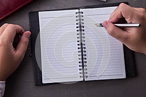 Top view of man hands writing on empty notebook with pen in office.