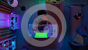 Top view of man in headset streaming playing game on computer with Chroma key green screen, talking with chat, lost