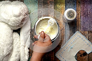 top view of man's hand grabbing a scoop of powdered baby milk next to stuffed baby bottle and bib. flat lay lat design