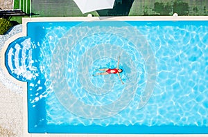 Top view of a man swimming in a swimming pool on warm and sunny summer day