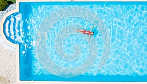 Top view of a man swimming in a swimming pool on warm and sunny summer day