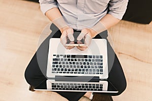 Top view man typing text message on his smart phone while sitting front open laptop computer, office man connecting to wireless v