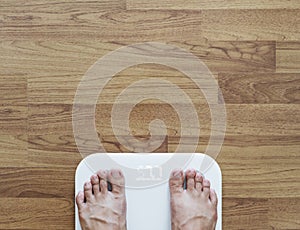 Top view, a man using body scale checking body weight, dieting and lose weight concept