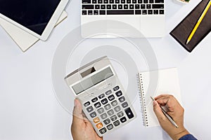 Top view. Man using calculator and writing make note.