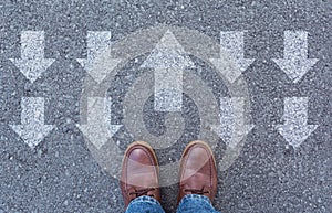 Top view of man wearing shoes choosing a way marked with arrows