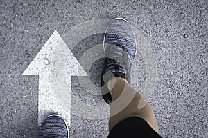 Top view of man wearing shoes choosing a way marked with white arrows. Chooses the right path concept