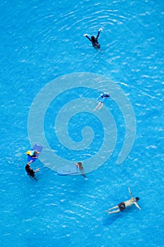 Top view of man, woman and children are relaxing and enjoy activities in the swimming pool of the luxury hotel and resort at