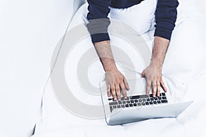 top view of a man working on his lap top the the bed