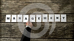 Top view of manager hand arranging ten white cards with letters