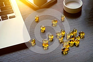 Top view of many capsules with omega-3 oil on a dark brown table
