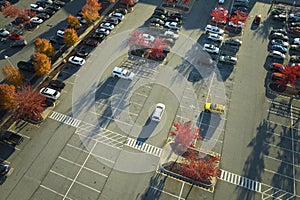 Top view of many cars parked on a parking lot in front of a strip mall plaza. Concept of consumerism and market economy