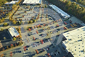 Top view of many cars parked on a parking lot in front of a strip mall plaza. Concept of consumerism and market economy