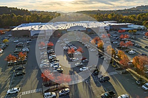 Top view of many cars parked on a parking lot in front of a strip mall plaza. Concept of consumerism and market economy