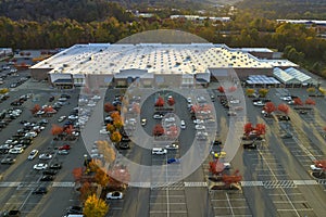 Top view of many cars parked on a parking lot in front of a strip mall plaza. Concept of consumerism and market economy