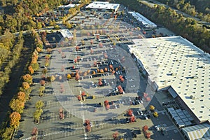 Top view of many cars parked on a parking lot in front of a strip mall plaza. Concept of consumerism and market economy