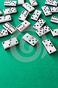 Top view of many domino pieces on green mat to play, vertically
