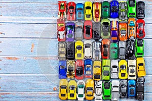 Top view of many little car miniature on wooden background from one child`s collection, showing an abundance and excess of things