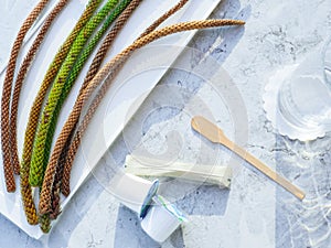 Top view of a marble pattern table with long pine cones on a tray, sugar stick, creamers and glass