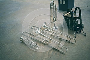 Top view of marching band instruments: trombones, trumpets, saxophones and euphonium drums laying on the floor.