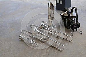 Top view of marching band instruments: trombones, trumpets, saxophones and euphonium drums laying on the floor.