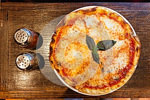 Top view of Margarita pizza topping with basil leaves served with oregano and chili powder