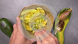 Top view of Mashing avocado in bowl. Preparing vegetarian avocado sauce. Cooking healthy food